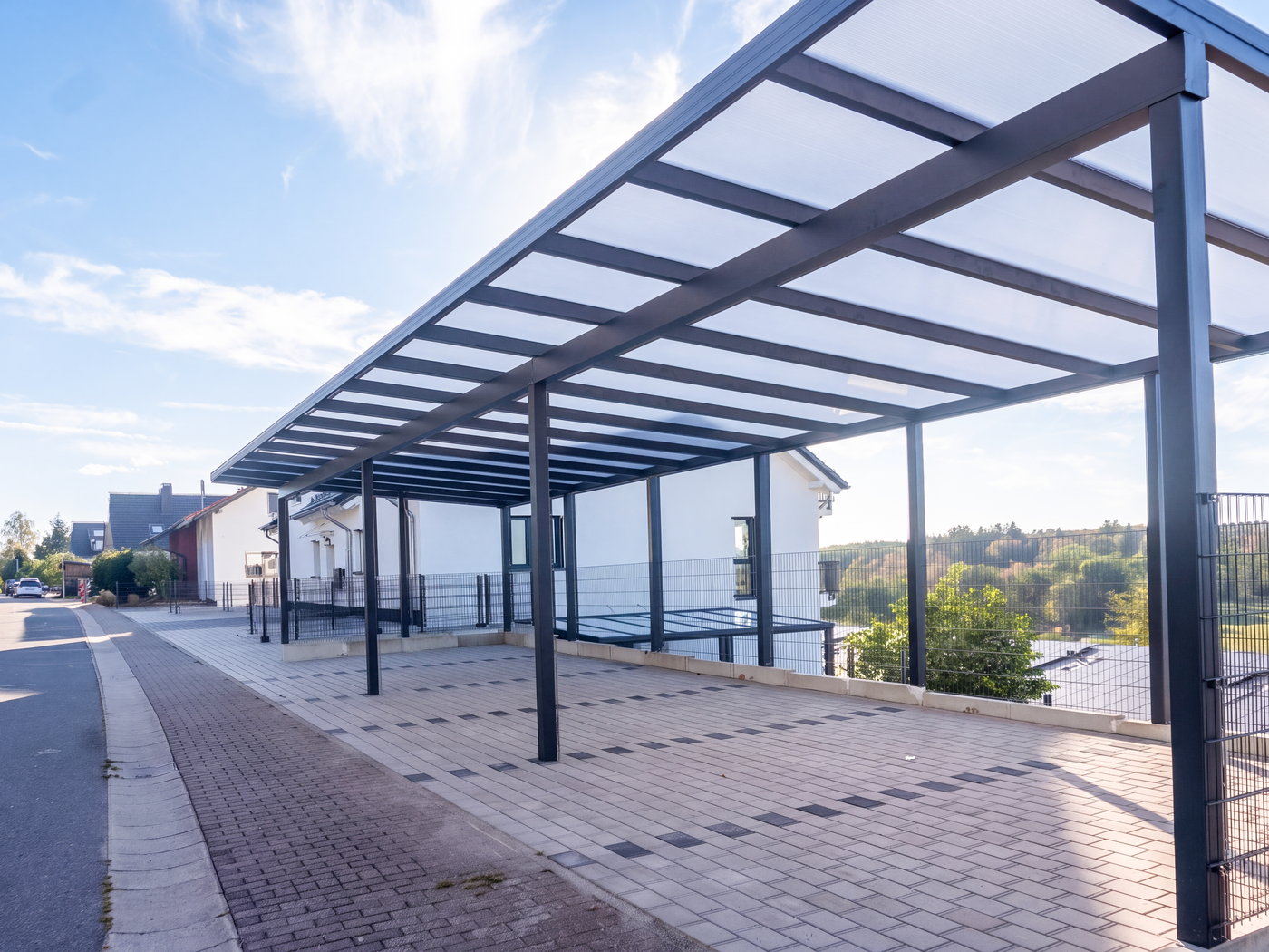 Carport mit lichtdurchlässigem Dach entlang der Stellplätze