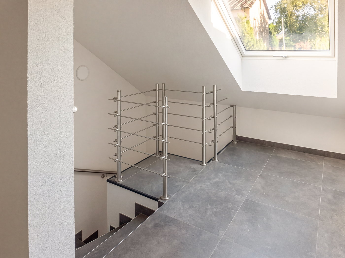 Treppenhaus mit Edelstahlgeländer und Dachfenster