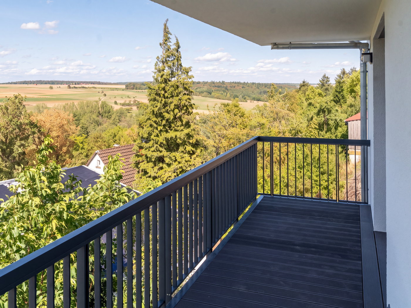 Balkon mit WPC-Belag, anthrazitfarbenem Geländer und Blick ins Grüne