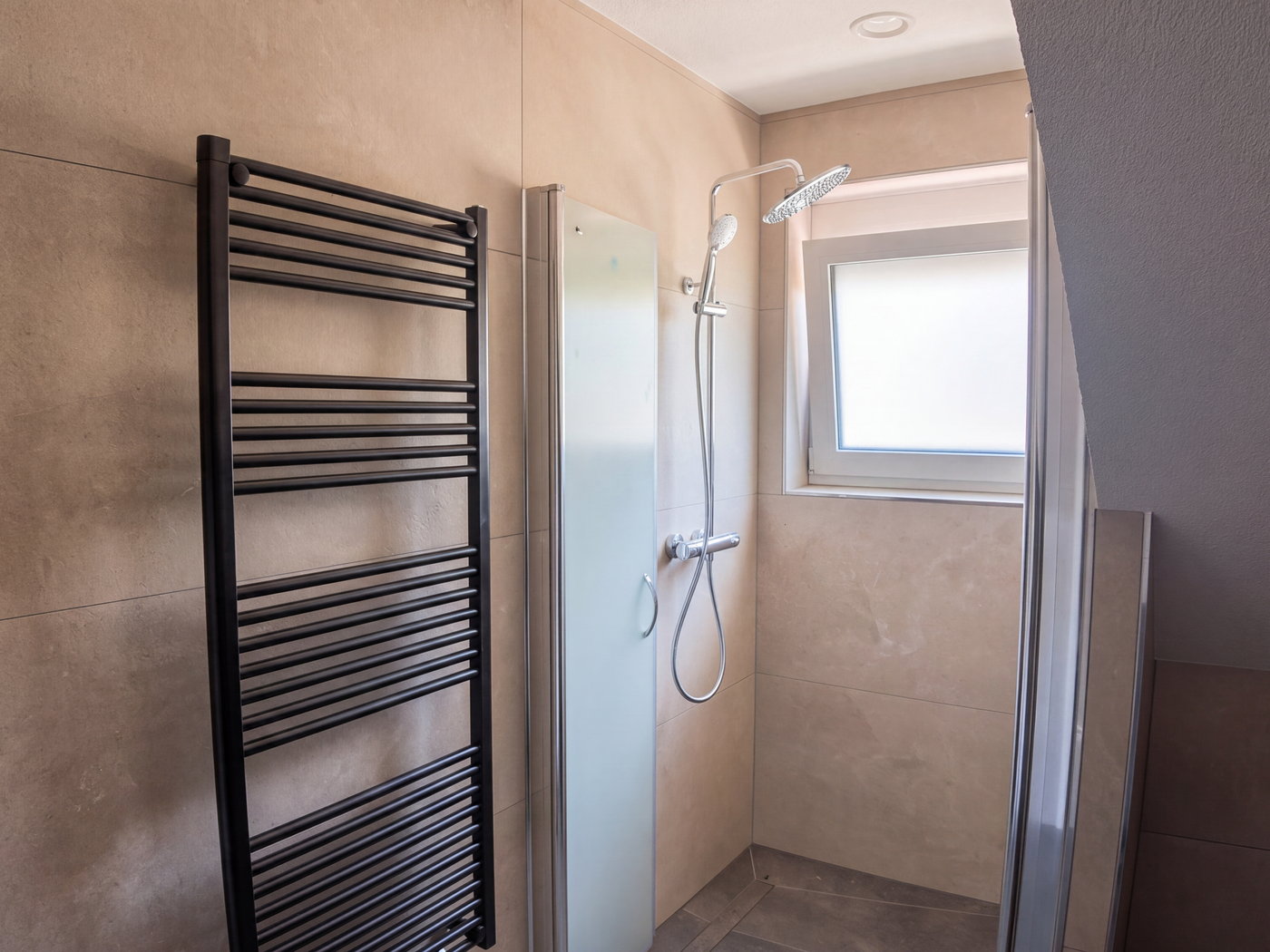 Dusche mit Kopfbrause und Handtuchheizkörper