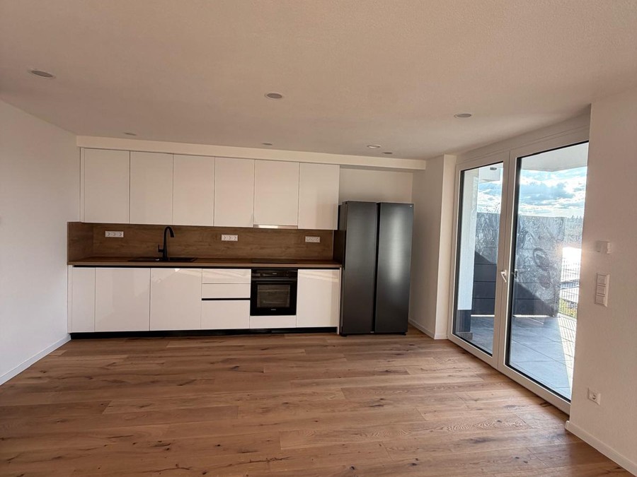 Einbauküche mit Kühlschrank und Zugang zur Terrasse