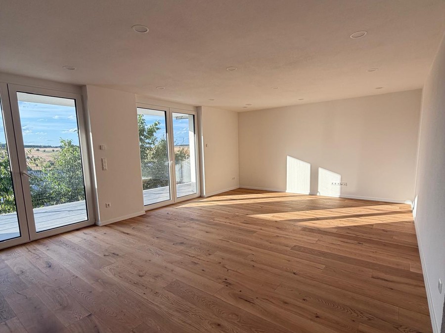 Wohnraum mit bodentiefen Fenstertüren und Eichenparkett